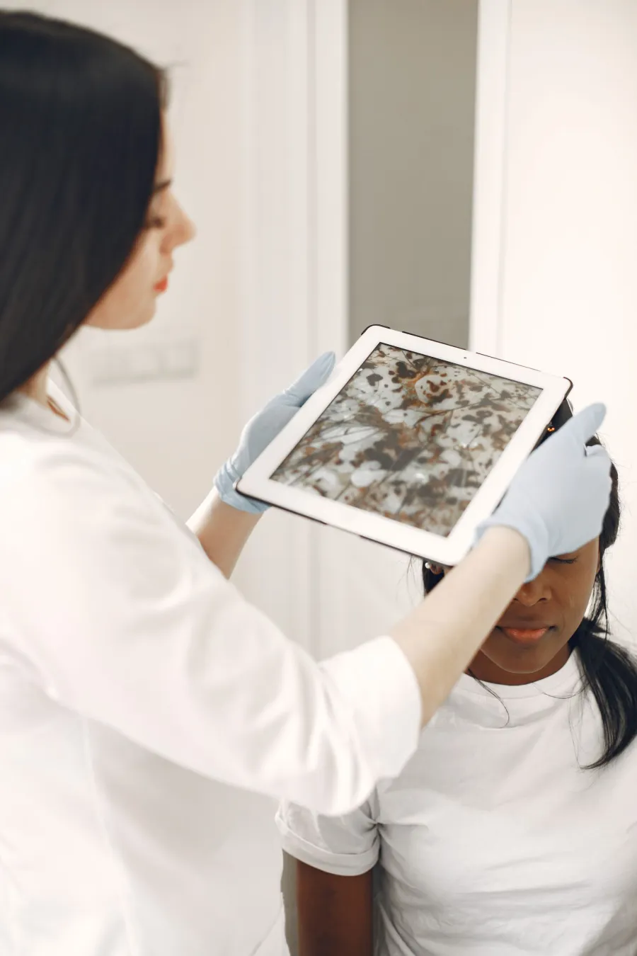 Healthcare professional examining a patient's skin with a tablet