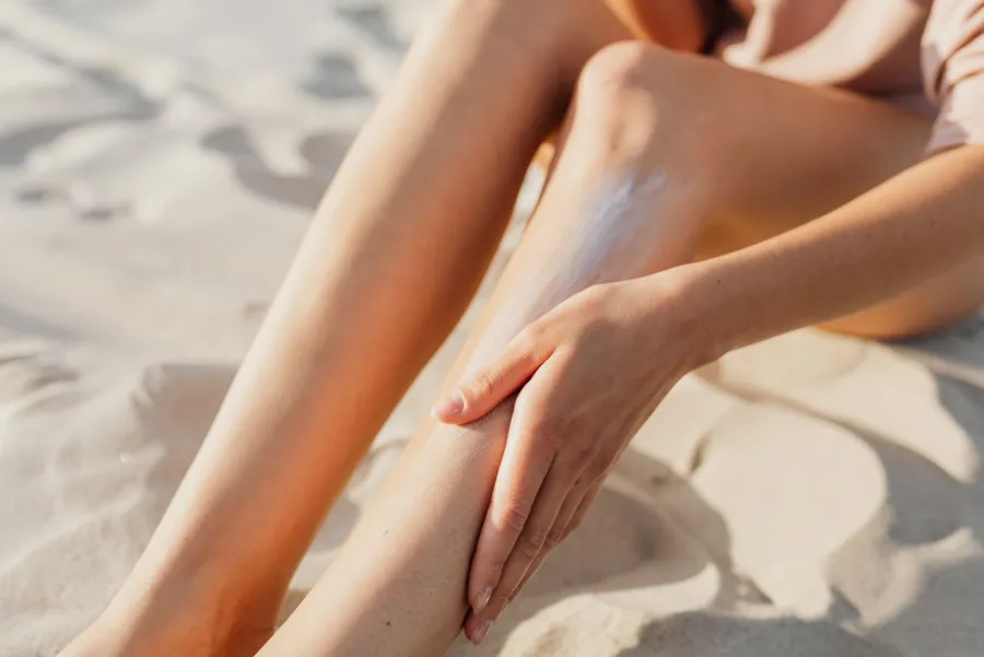 Close-up of a person applying sunscreen to their legs