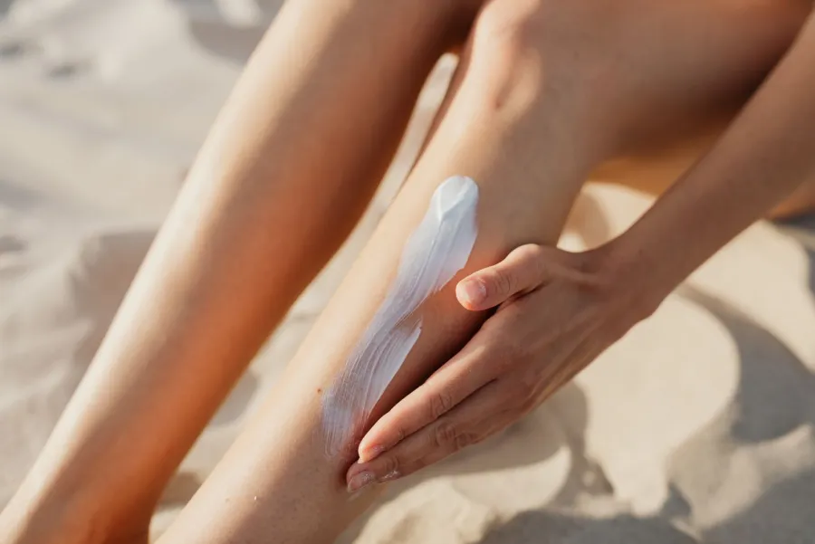 Person applying sunscreen or lotion to their leg