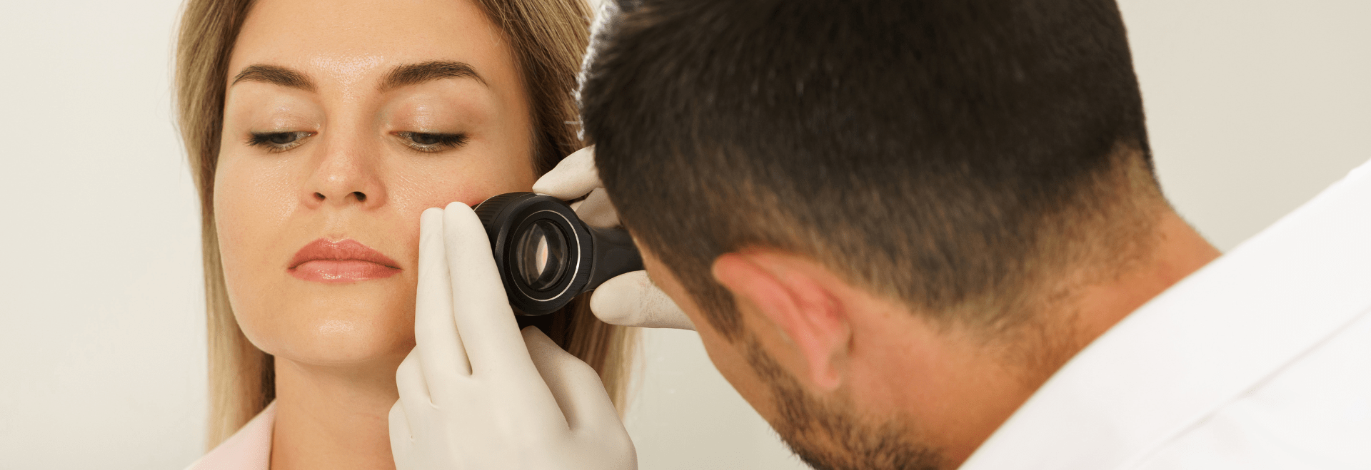 A doctor examining the patient's skin on the left cheek