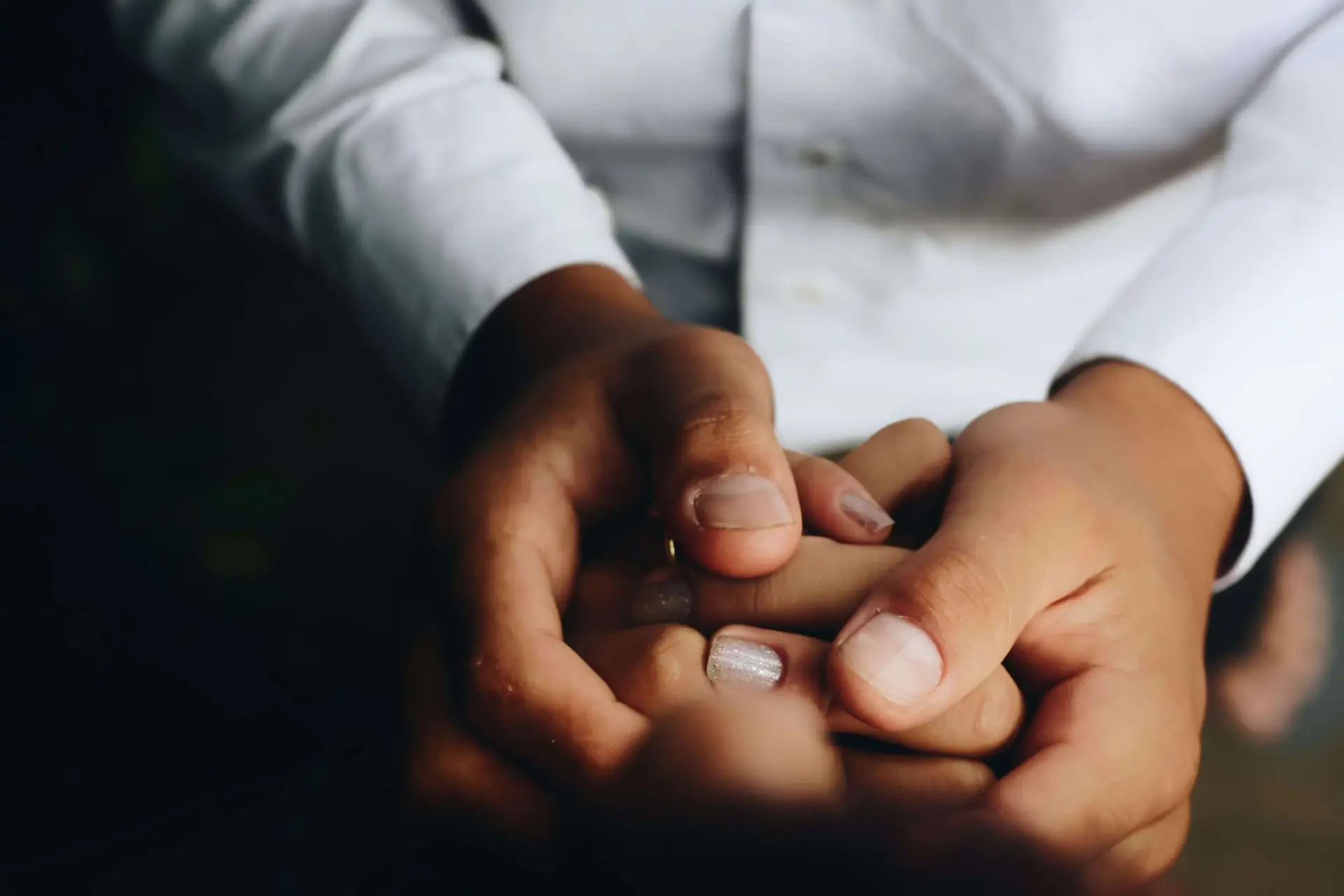 A father and a daughter holding their hands together.