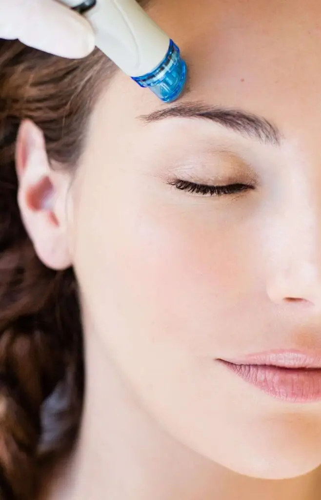 Close-up of woman receiving Hydrafacial treatment on her forehead.