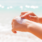 A person applying sunscreen on a beach.