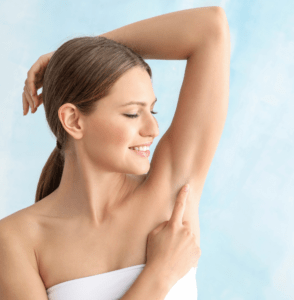 Smiling woman with raised arm checking her underarm, promoting skin health and personal care