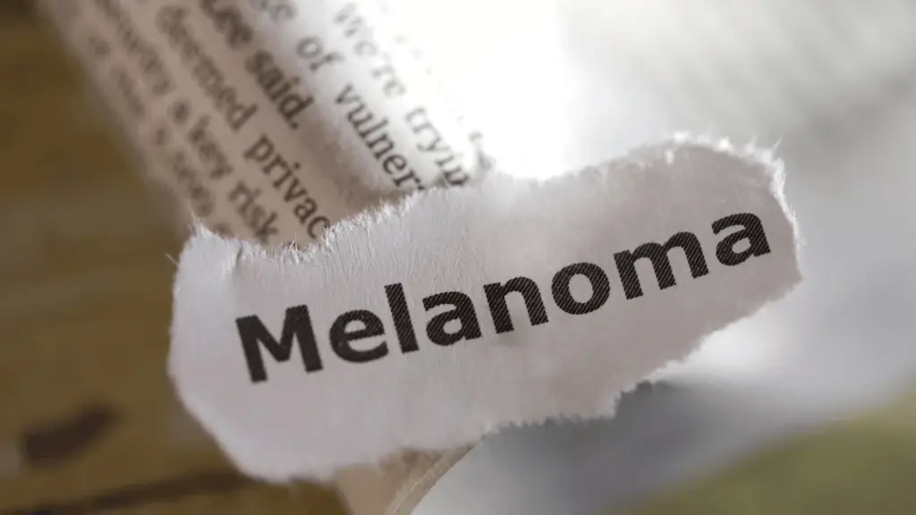 Close-up of torn paper strip showing the printed word “Melanoma.”