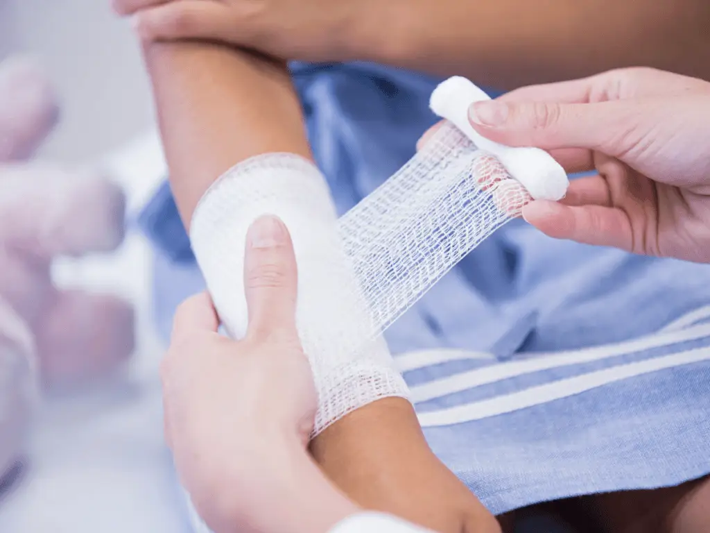 Medical professional's hands wrapping the bandage around the patient's wounded hand