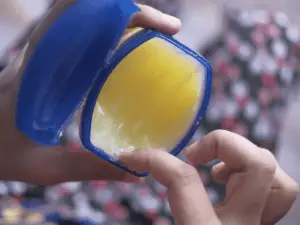 A close-up image of a person's hand taking the cream out of the cream box