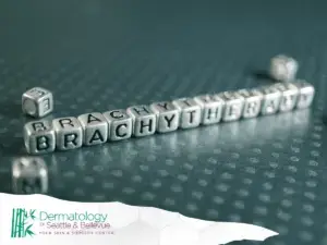 Close-up of letter blocks spelling 'BRACHYTHERAPY' on a textured surface, with the Dermatology of Seattle & Bellevue logo in the corner.
