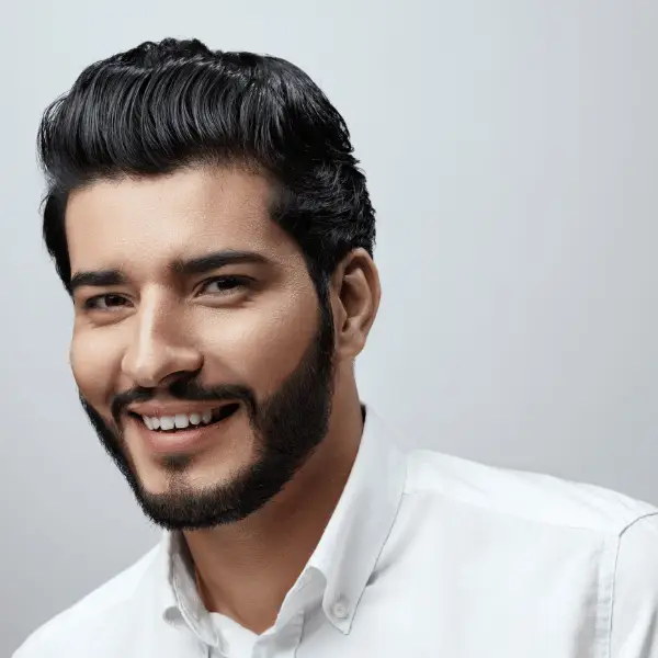 Portrait of a smiling man with well-groomed dark hair and beard, wearing a white shirt.