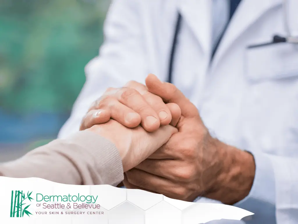 Doctor holding a patient's hand in a reassuring manner at a dermatology clinic.