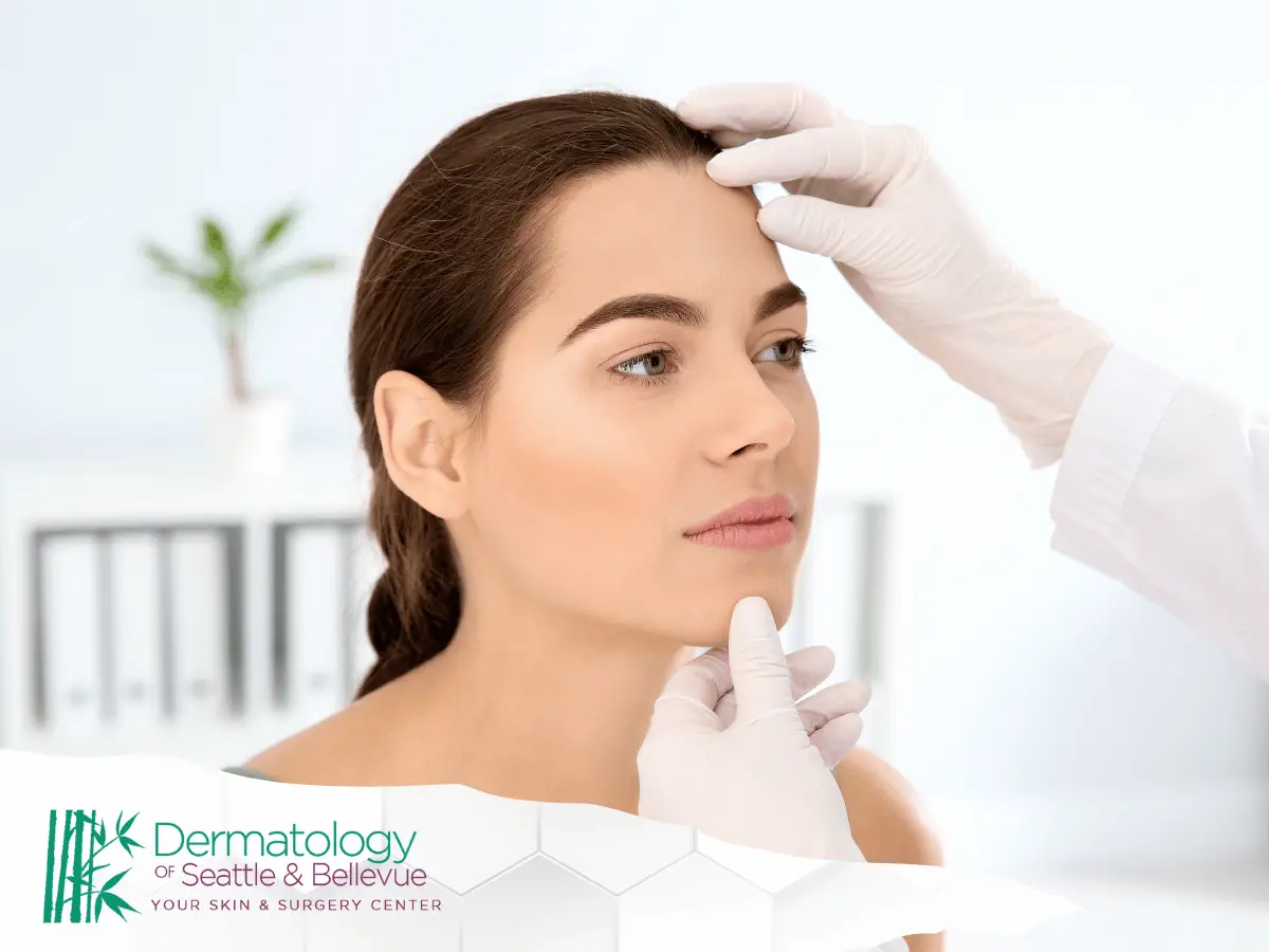 A professional assessing the facial skin of a young female patient in a clinical setting.