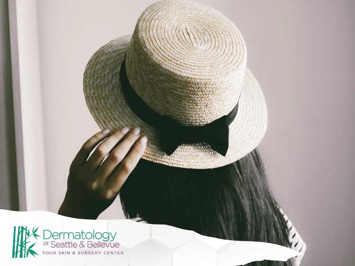 Person wearing a straw hat with a black ribbon, viewed from behind, representing sun protection and skin health awareness.