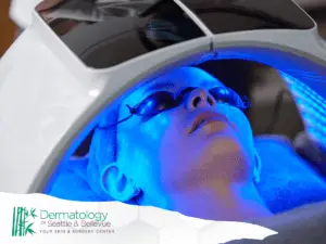 Person lying under blue LED light therapy device wearing eye shields