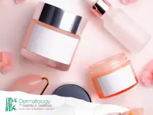 Skincare jars and dropper bottle on pink background with flower petals