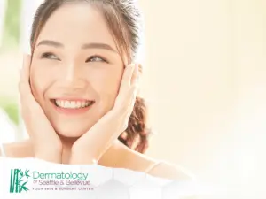 Smiling young woman touching her cheeks in bright, soft lighting