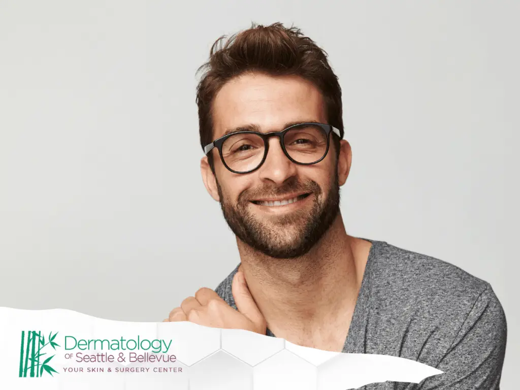Smiling man with beard and glasses against light gray background