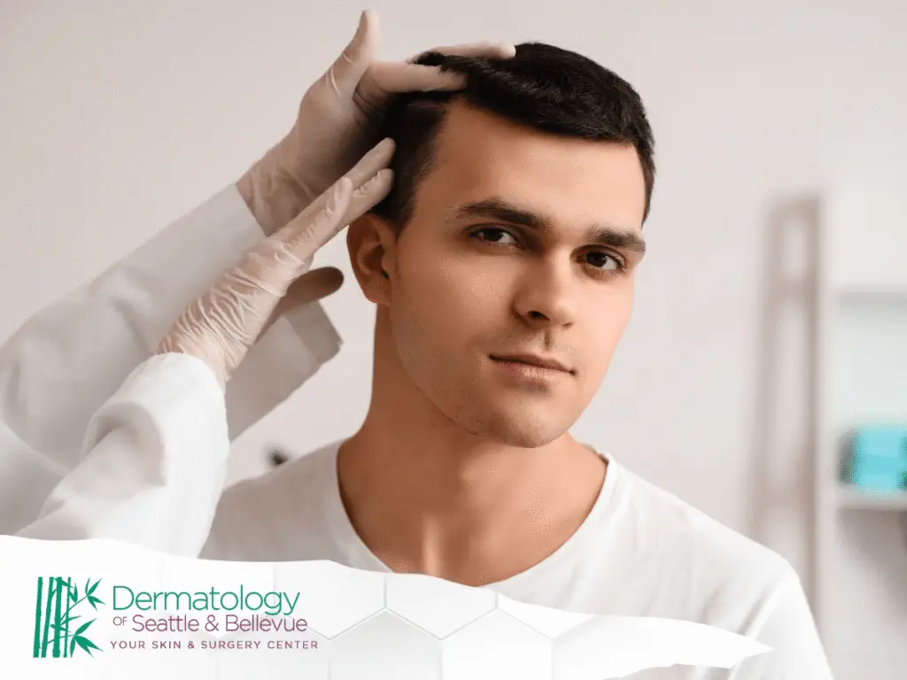 Dermatologist examining young man’s scalp with gloved hands indoors