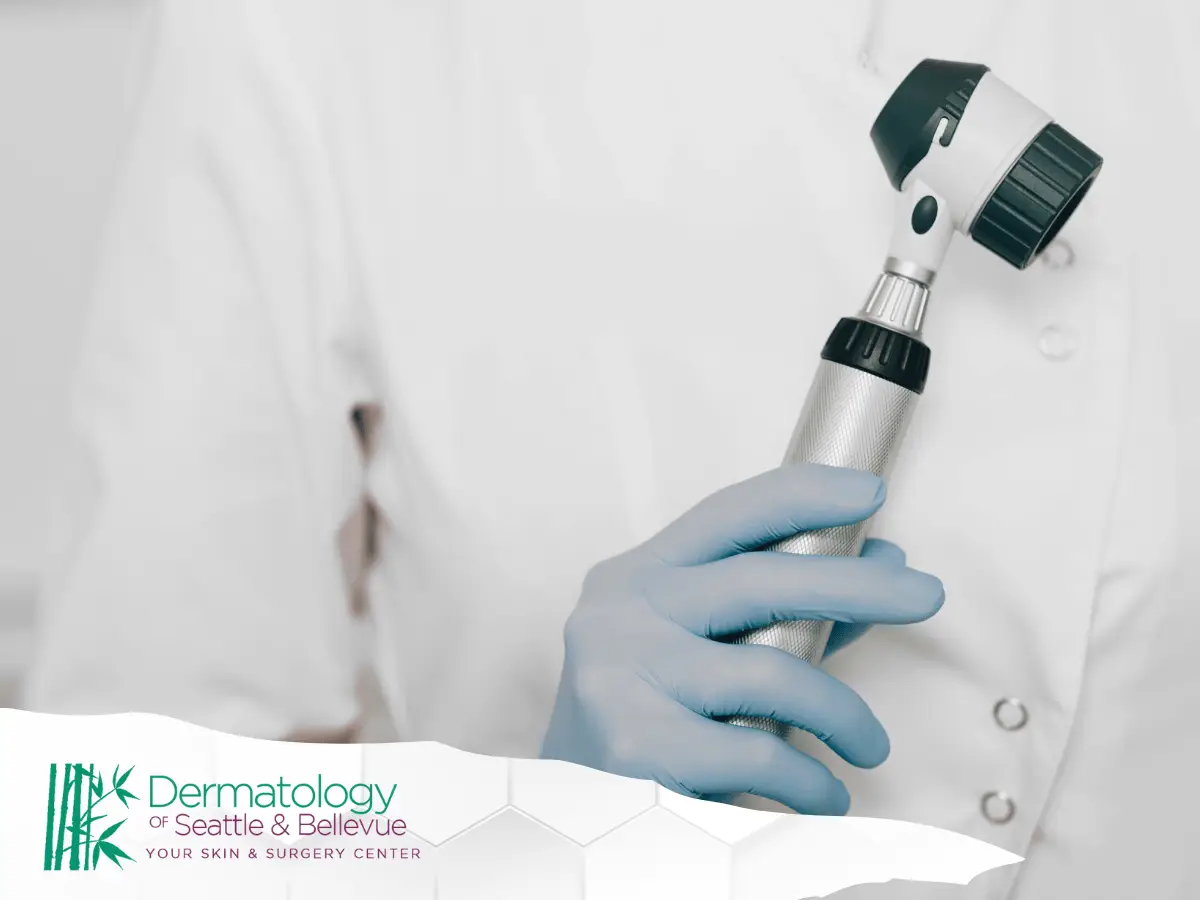 Gloved hand holding a dermatoscope against white medical coat