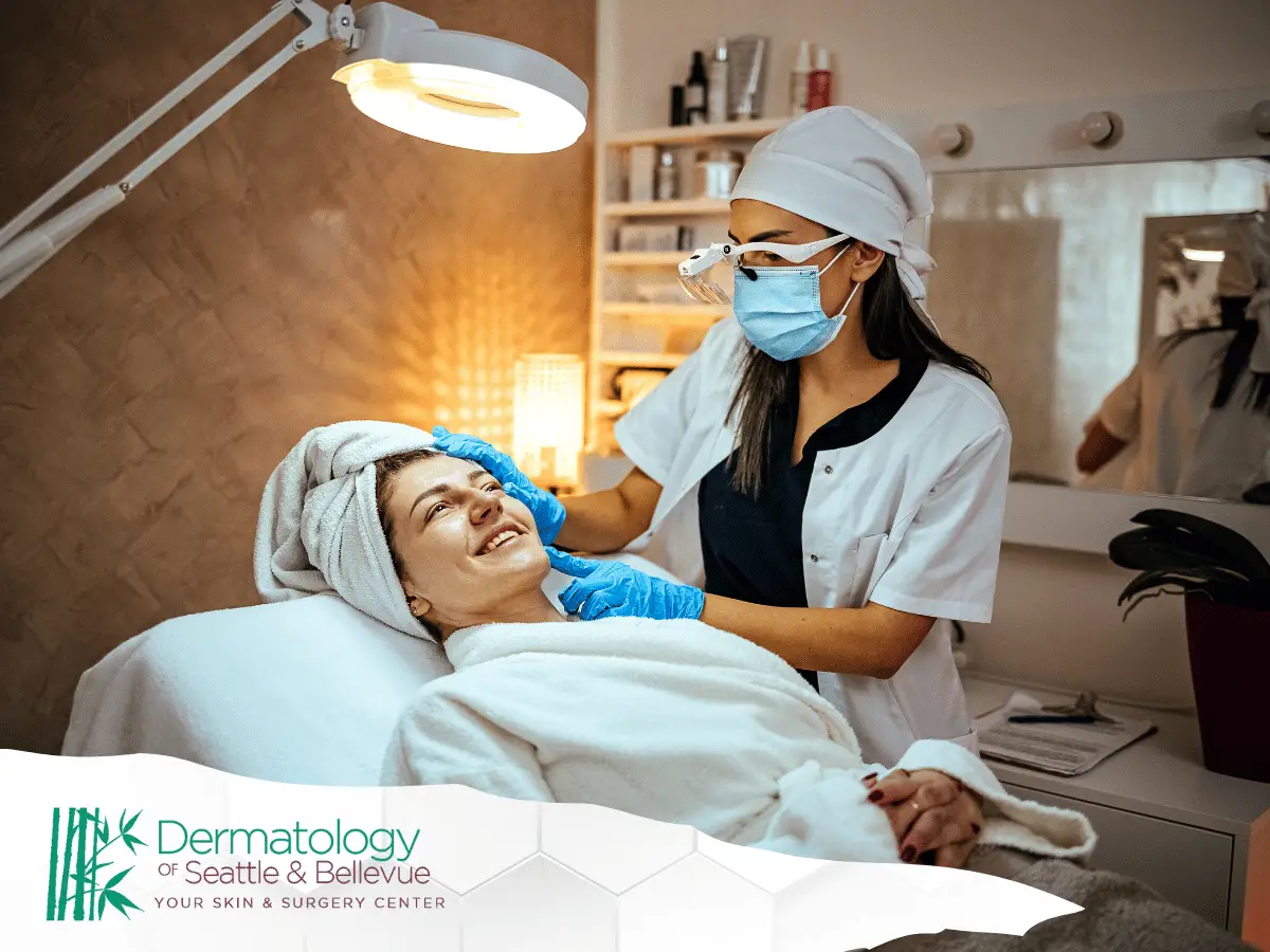 Esthetician in mask treating smiling woman on spa bed.
