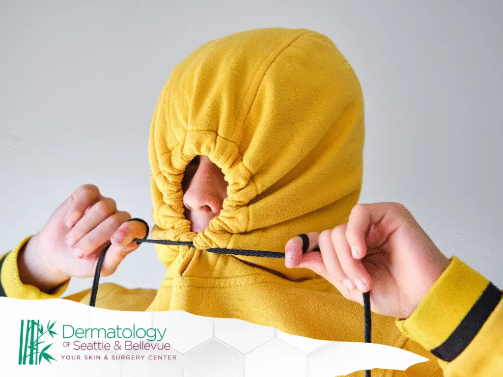 Person tightening yellow hoodie around face with drawstrings