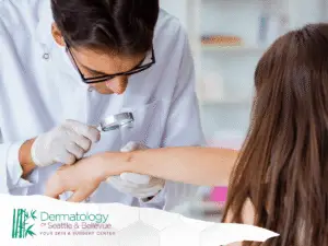 Dermatologist examining a child’s forearm lesion with magnifying glass