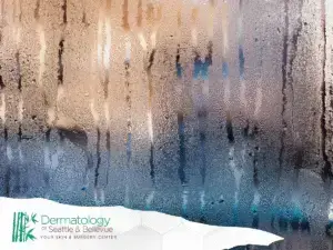 Fogged glass with vertical water streaks and blurred warm lights.