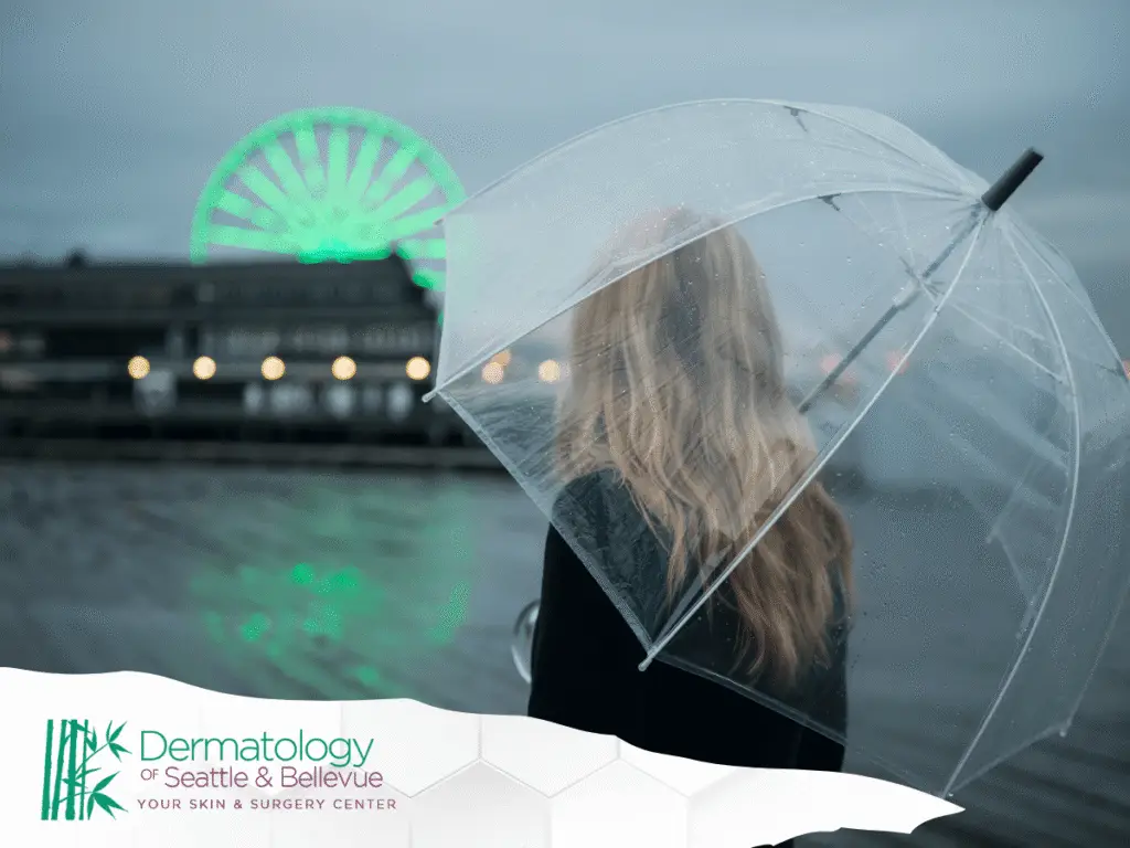 Woman with clear umbrella overlooking waterfront and glowing green ferris wheel.
