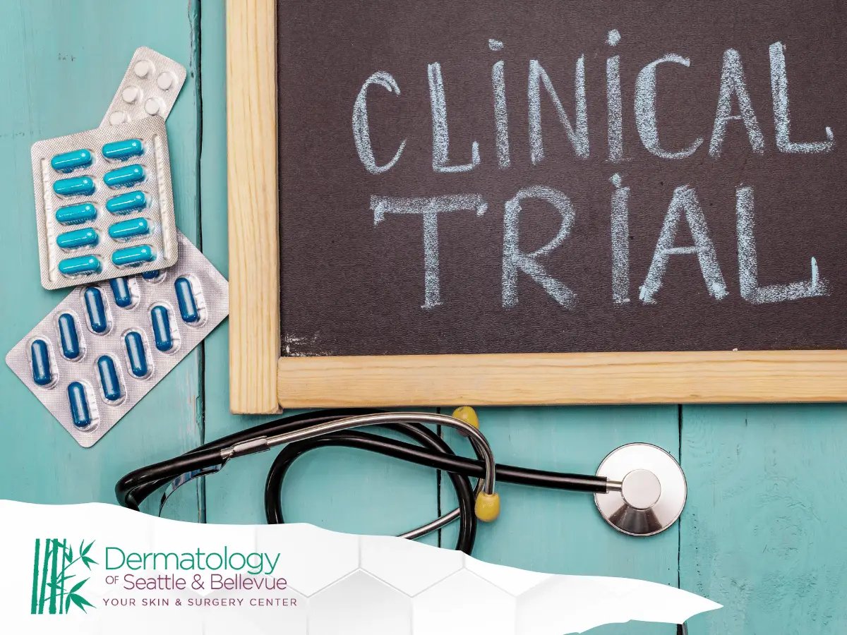 Chalkboard reading “CLINICAL TRIAL” with pills and stethoscope on teal surface