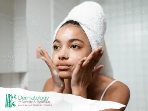 Young woman with towel on head washing her face.