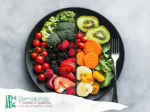 Black plate of colorful fruits and vegetables divided down middle.