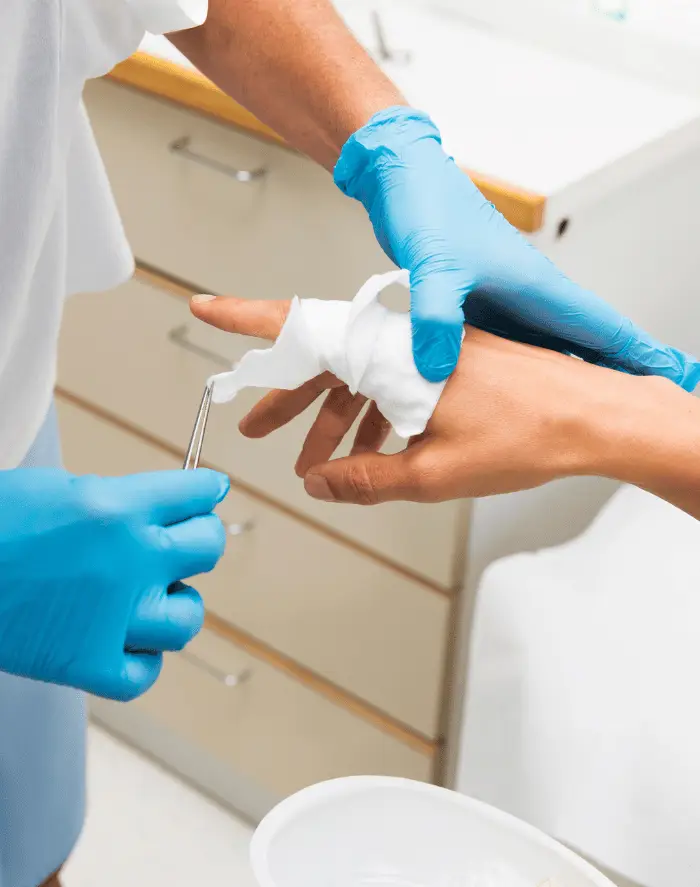 Healthcare worker bandaging a patient’s injured finger with gauze.