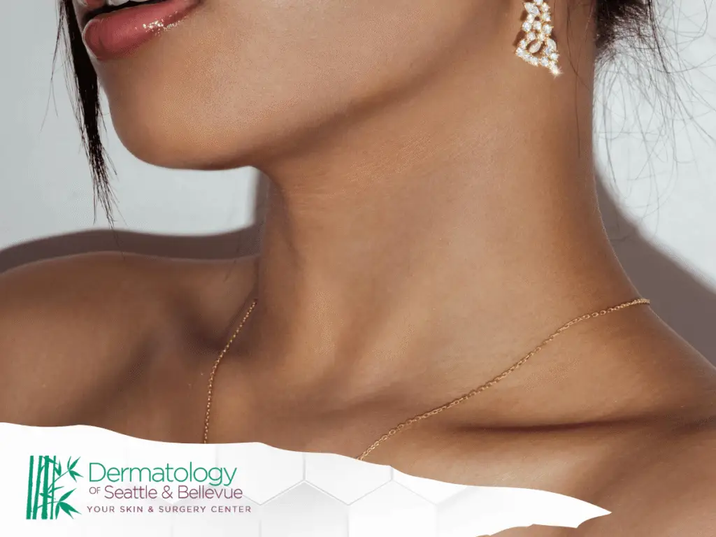 Close-up of woman’s neck with gold necklace and dangling earring.