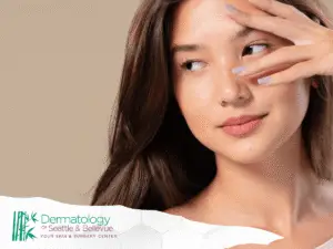 Young woman with long brown hair touching her face thoughtfully.