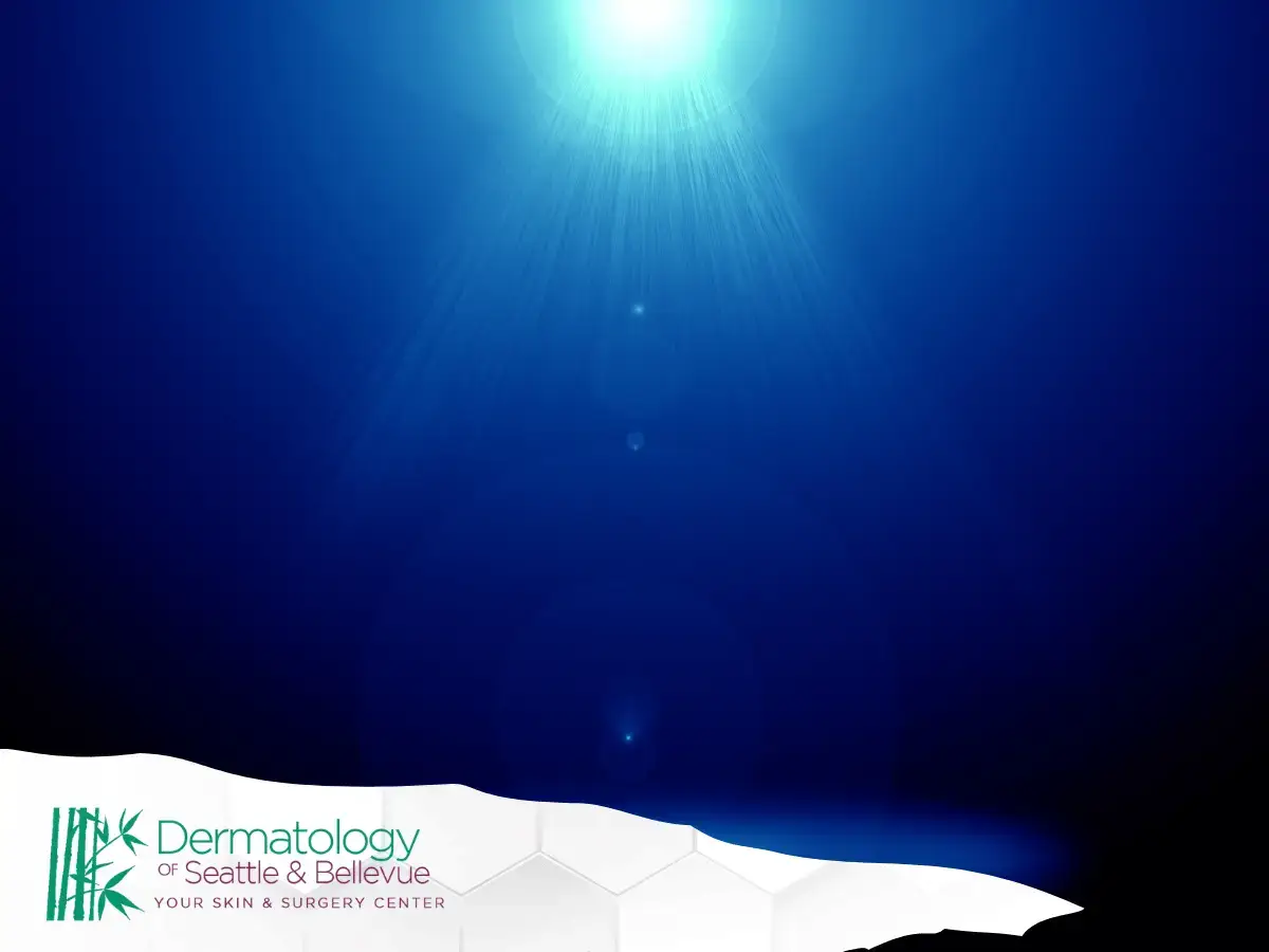 Bright blue light rays shining downward over dark blue background.