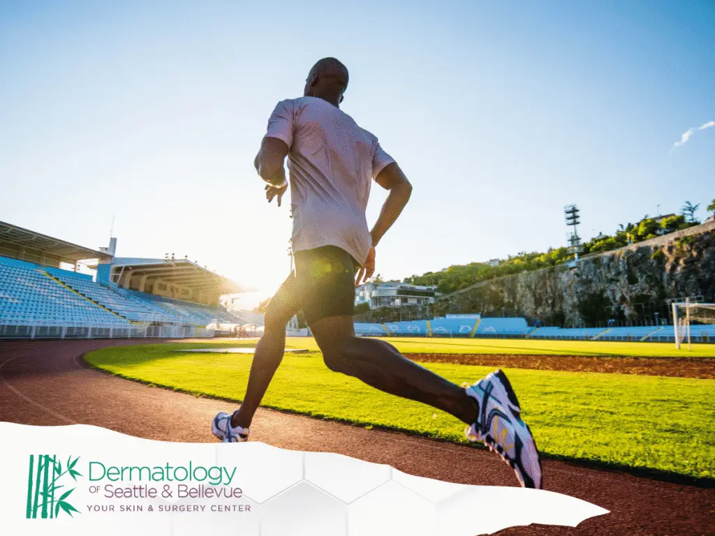 Man running on outdoor track at stadium during sunset.