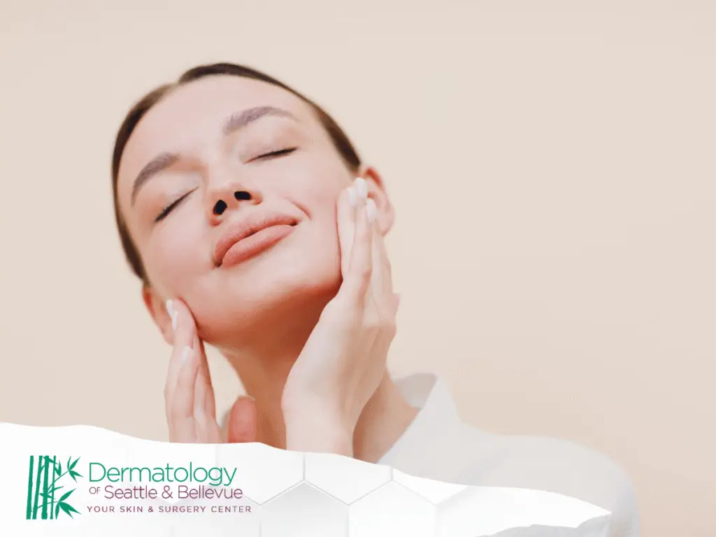 Woman with closed eyes gently touching her face, neutral background.