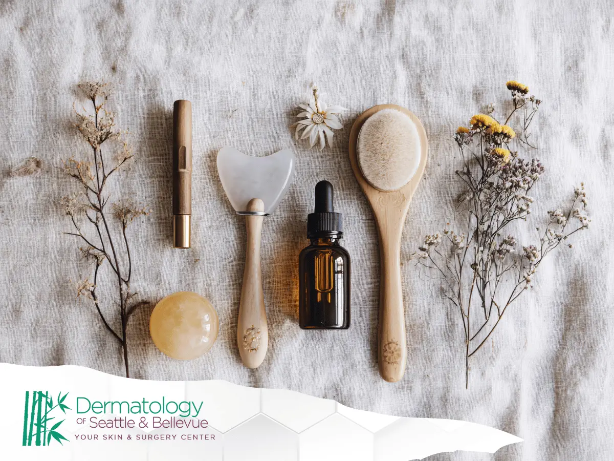 Flat lay of natural skincare tools, dropper bottle, and dried flowers