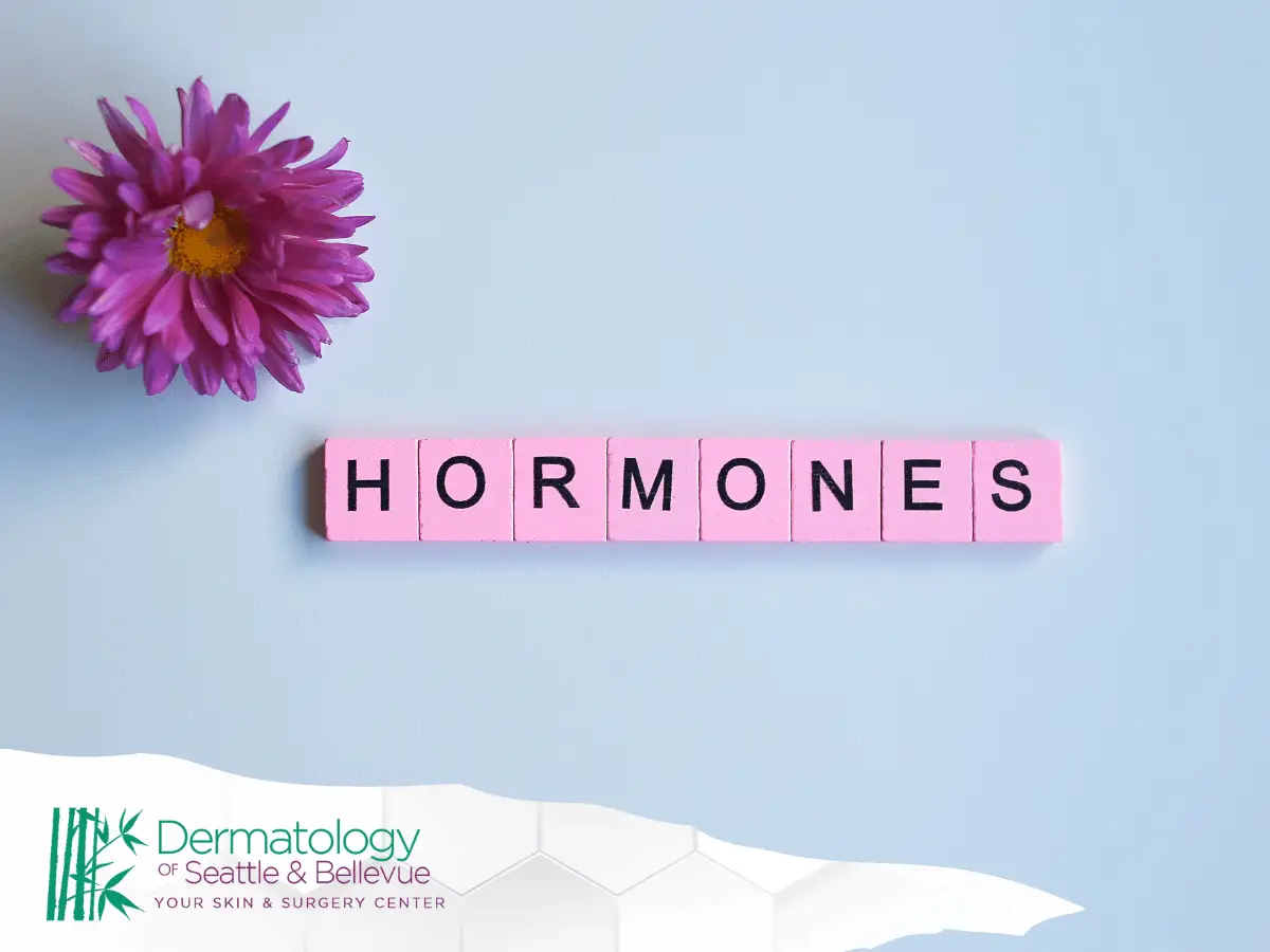 Pink flower and pink tiles spelling “HORMONES” on light blue background.