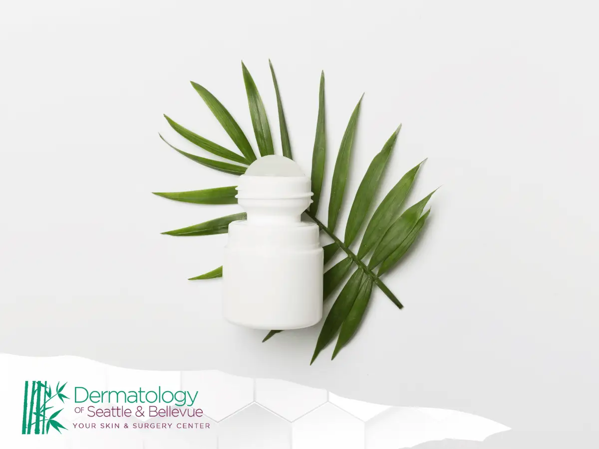 White roll-on bottle on green palm leaves against white background