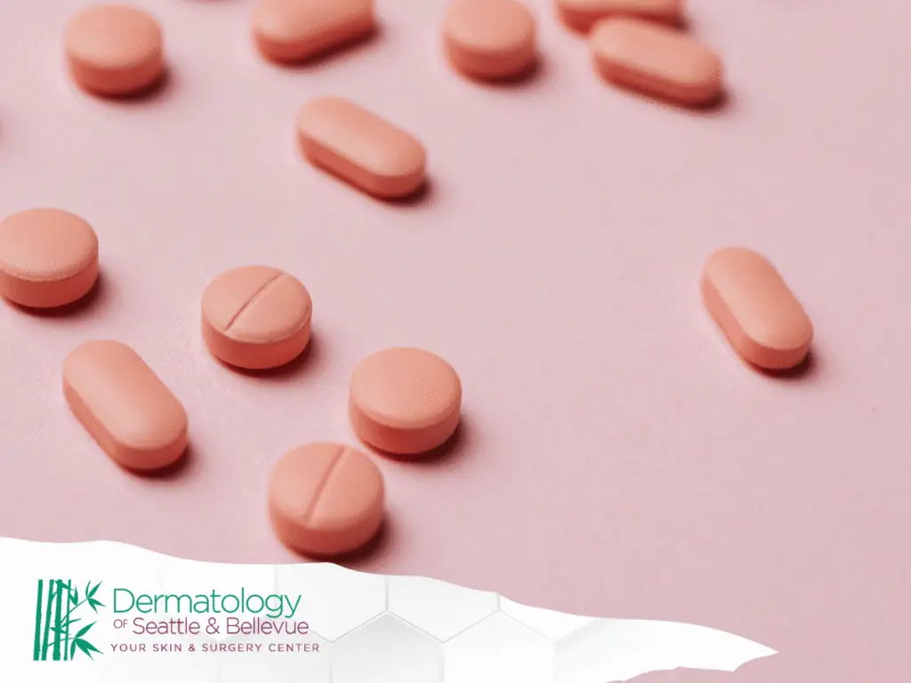 Pink tablets scattered on a pink surface, close-up view.