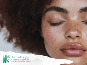 Close-up of freckled woman with closed eyes and glossy lips.