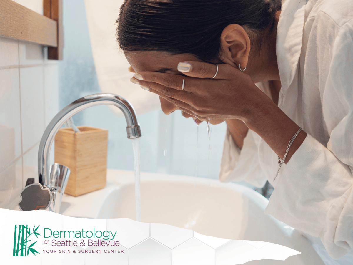 Woman washing her face over a sink in a well-lit bathroom.