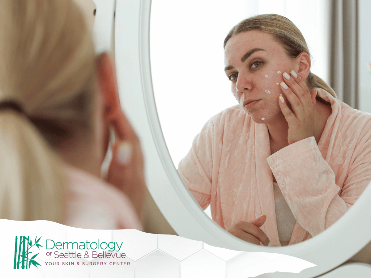 Woman applying skincare cream to her face in front of a mirror.